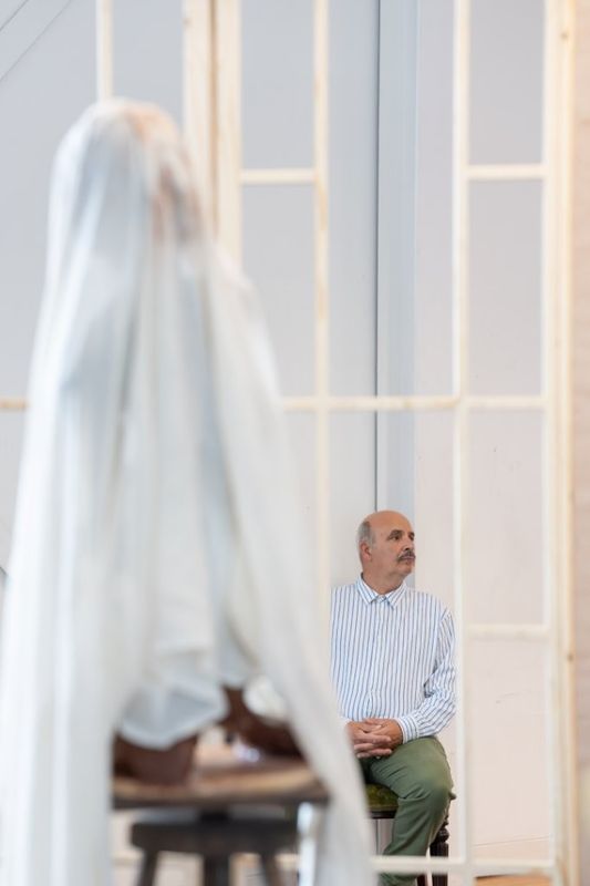A man can be seen in the background, there is something covered in a white sheet in front of him