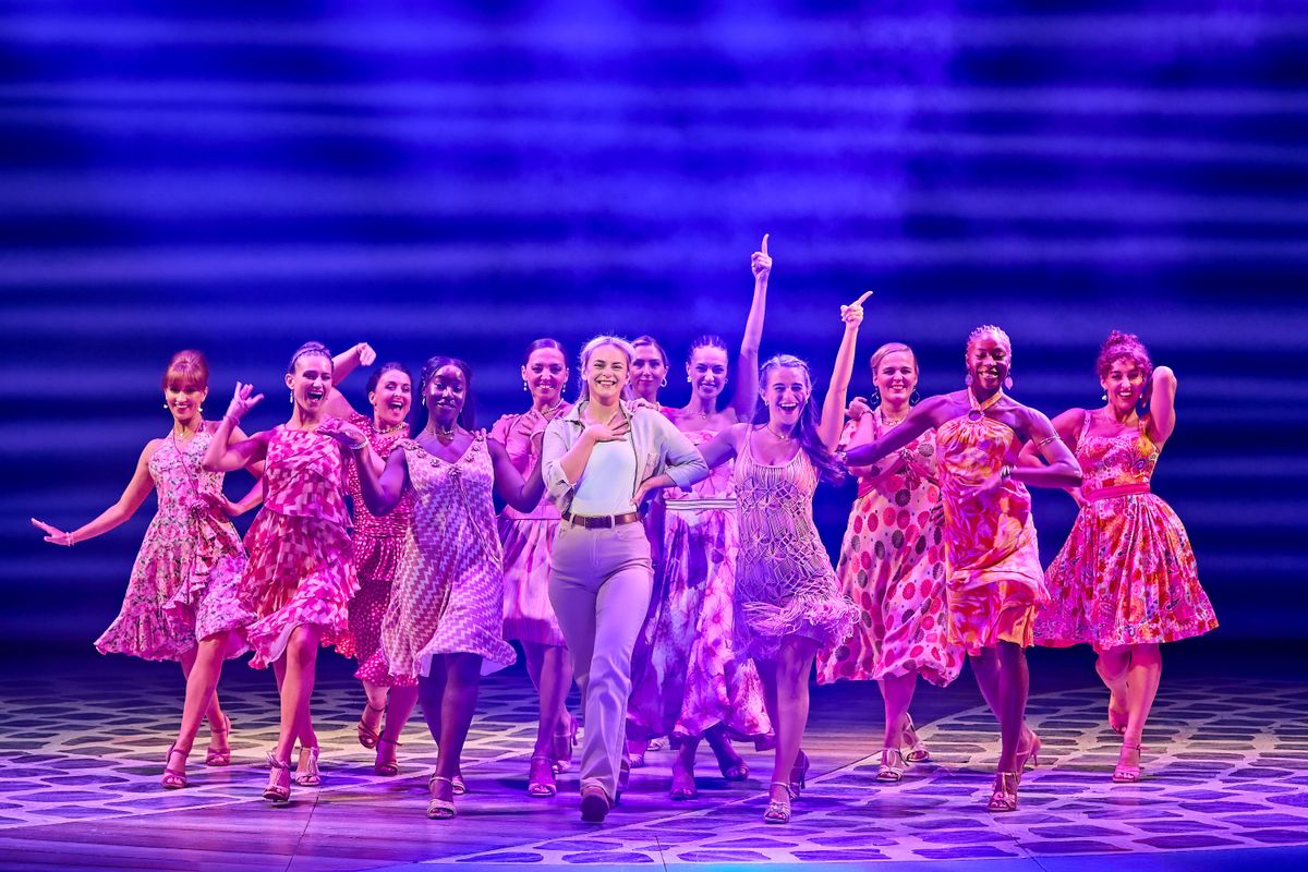Sophie is surrounded by the ensemble walking towards the front of the stage.
