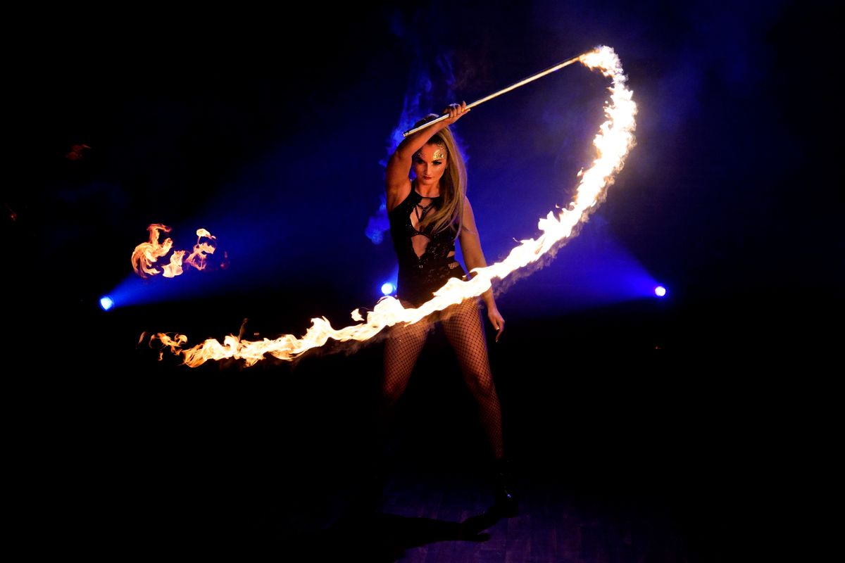 A circus performer surrounds themselves with fire.