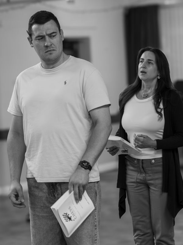 A man and a woman, they are both holding scripts, the woman is behind the man.