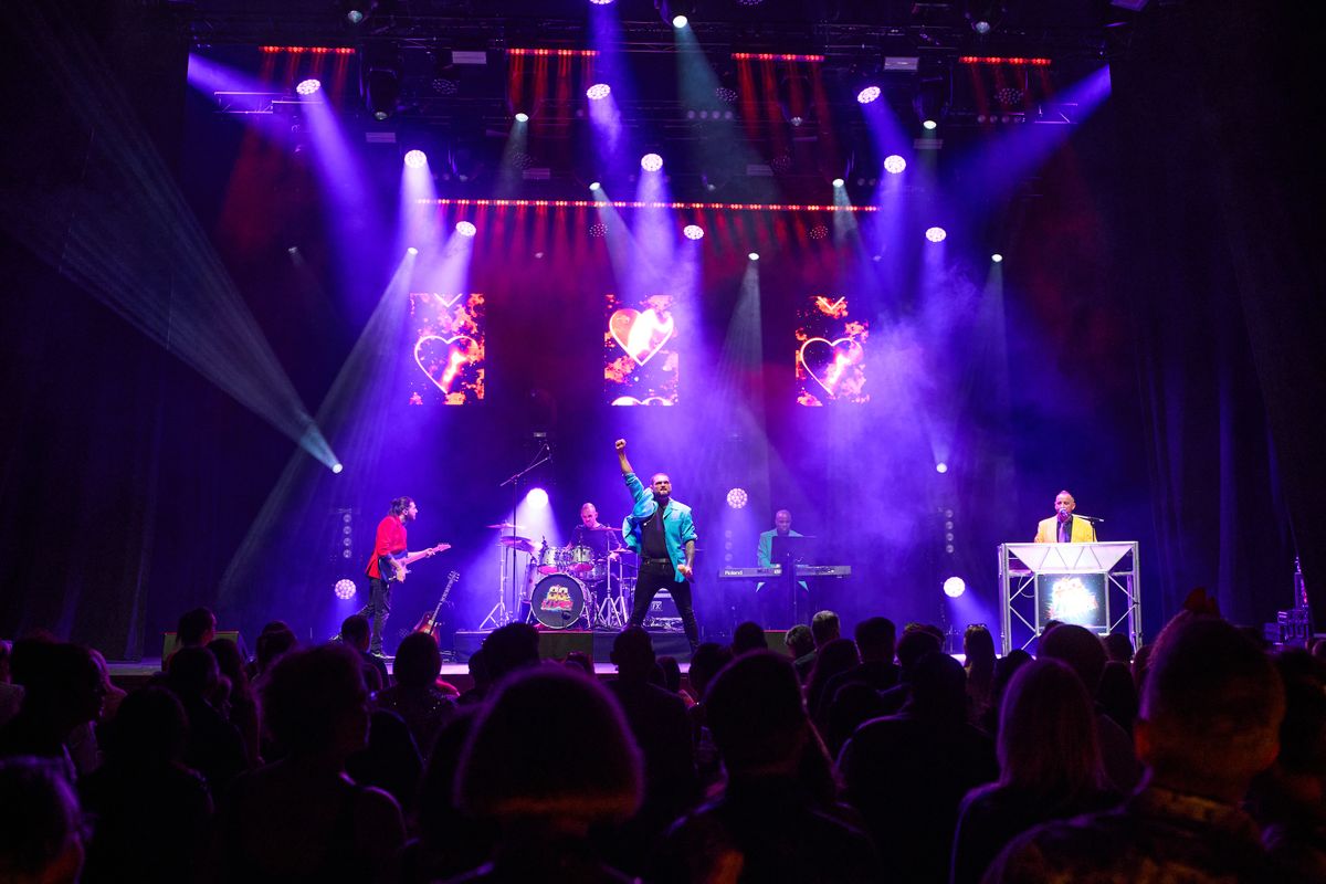 A person wearing a turquoise blazes raises their fist in the air.