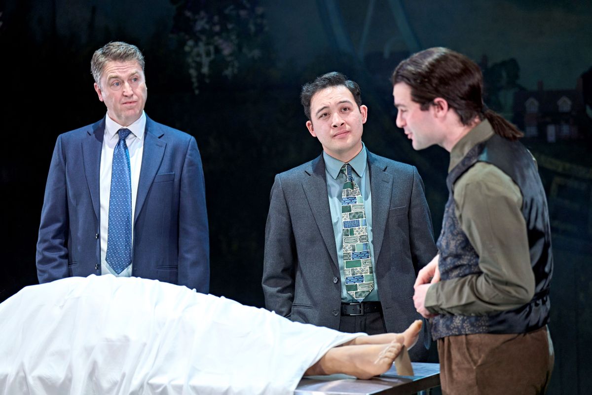 Three people stand over a body.