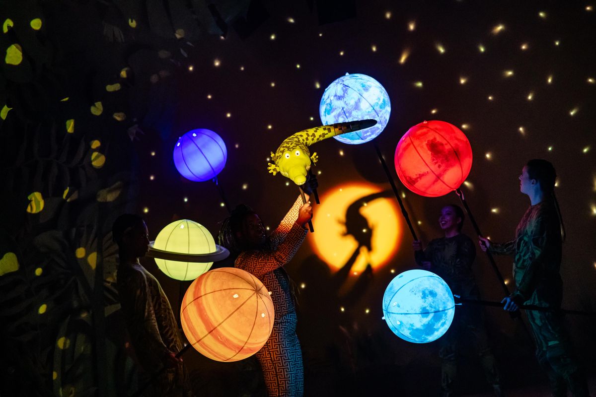 The planets are glowing in the dark and a smaller version of the crocodile is in the middle of them