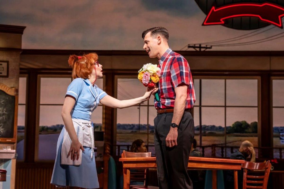 A waitress appears to be grabbing a bunch of flowers from a gentlman