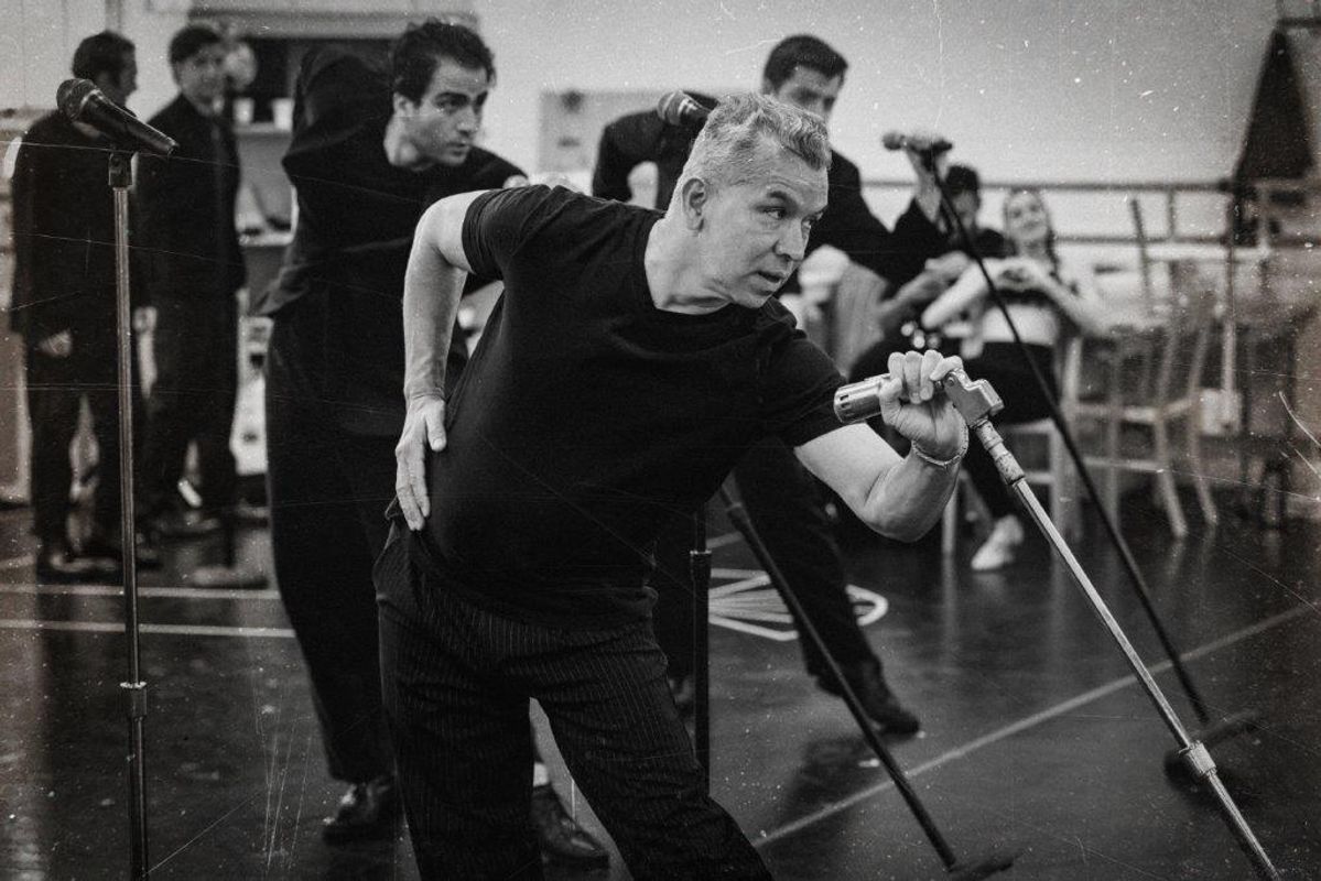 Black and white image of cats members rehearsing for Jersey boys. They are all wearing black and in a rehearsal studio