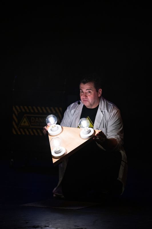 A person holds three light bulbs attached to a wooden triangle.