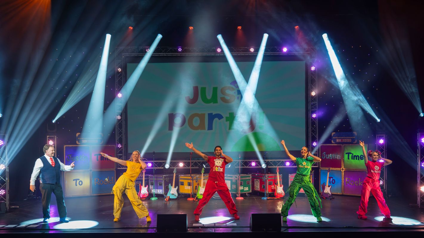 Justin and the ensemble stand on the stage with the ensemble dancing.