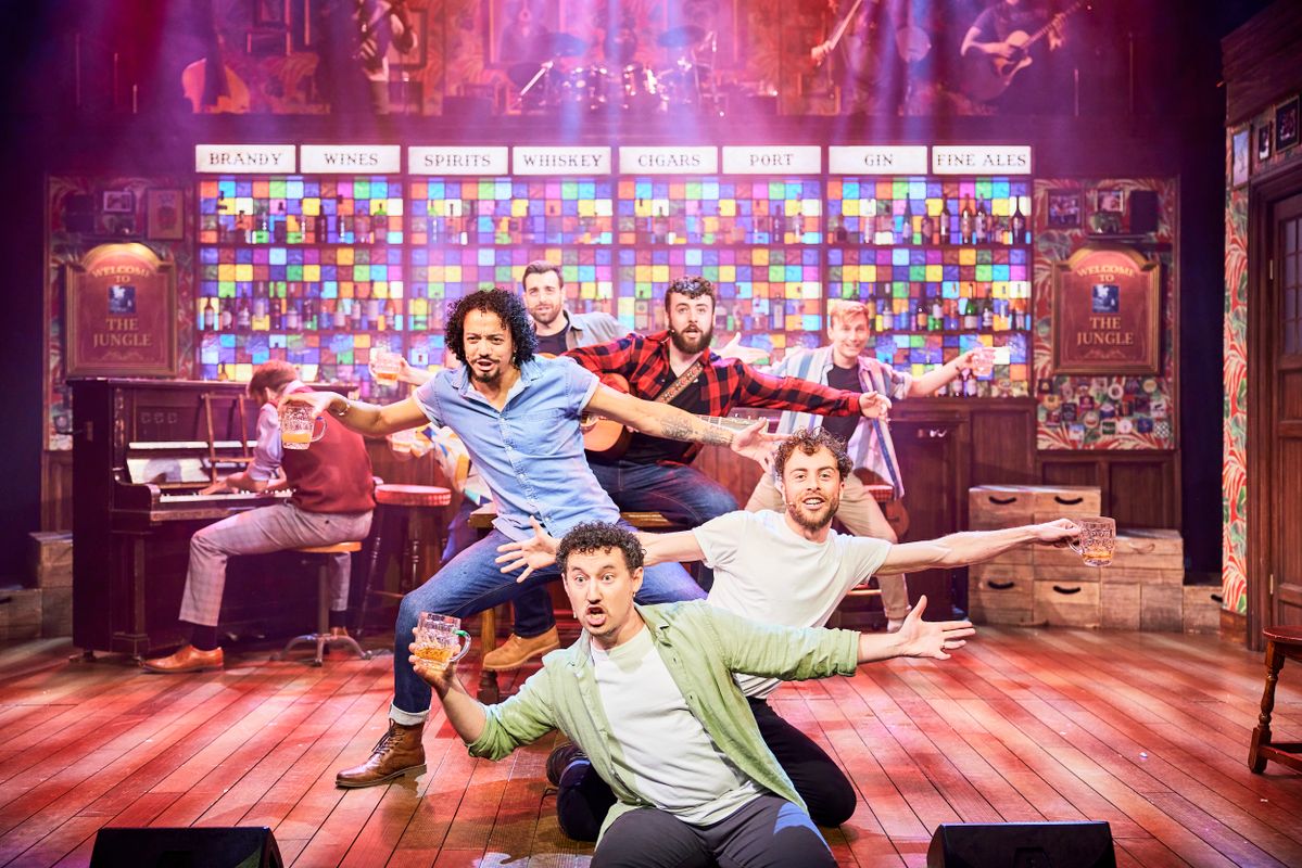 Six people stand one in front of the other holding beers to the side.