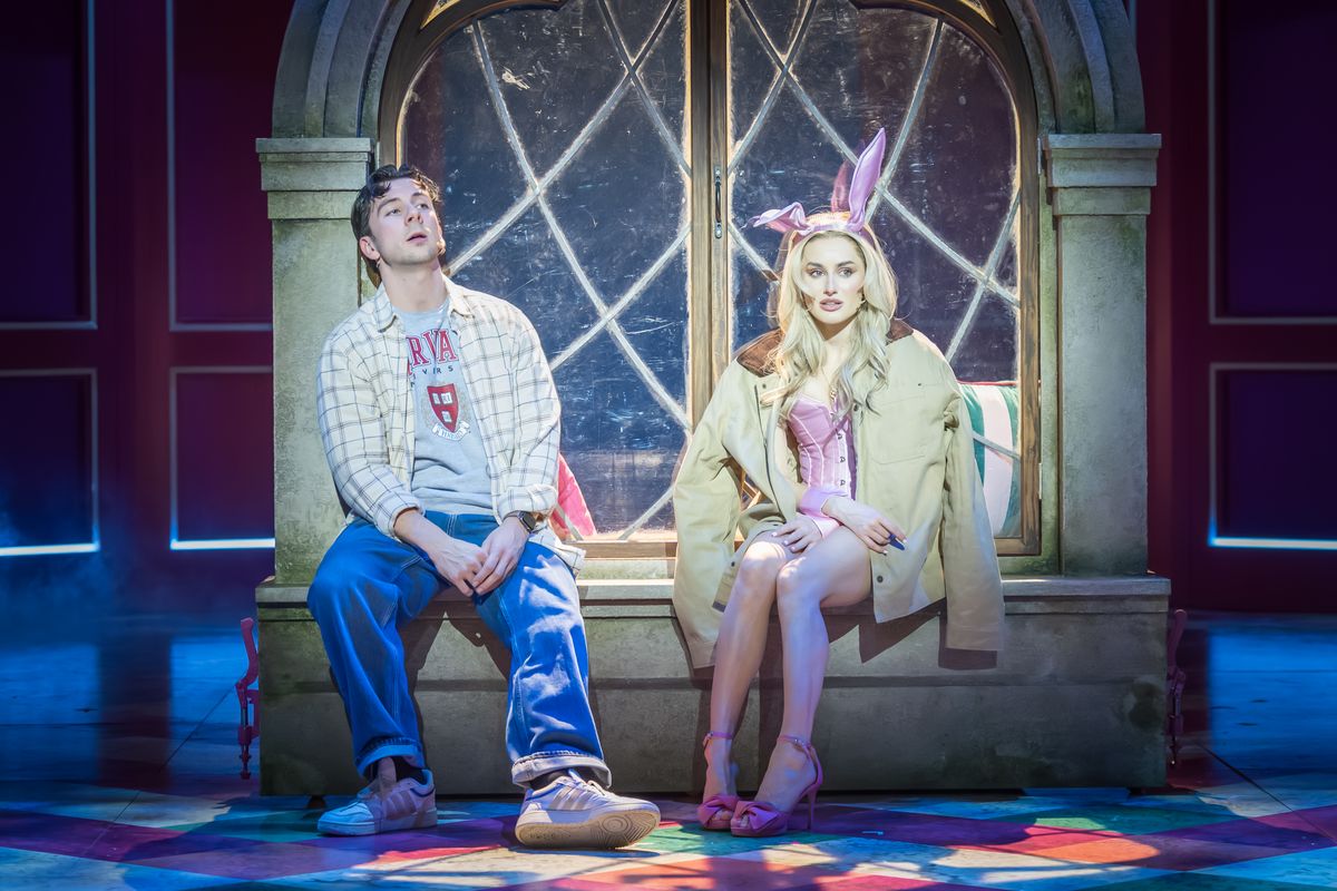 Two people sat on a ledge, one is wearing bunny ears