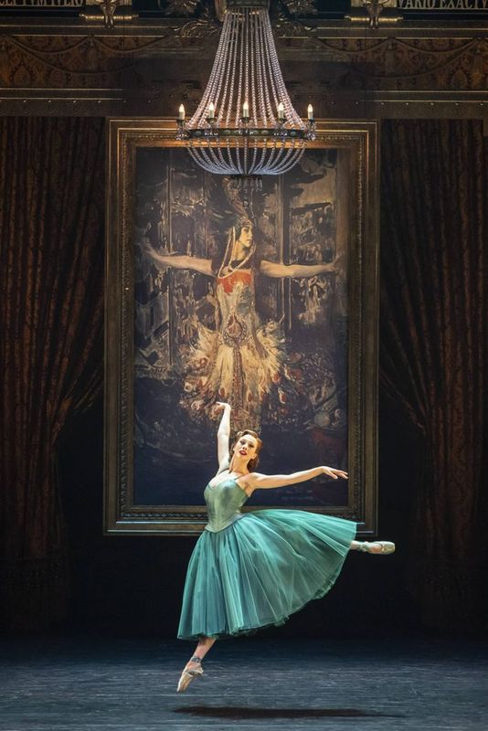 A dancer dressed in green leaps in the air.