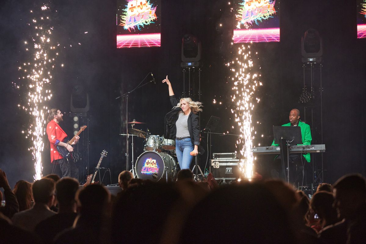 A person wearing a striped t shirt raises their right arm in the air.