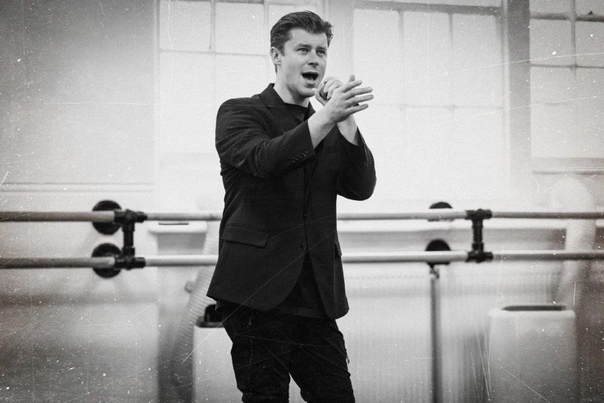 Black and white image of cats members rehearsing for Jersey boys. They are all wearing black and in a rehearsal studio