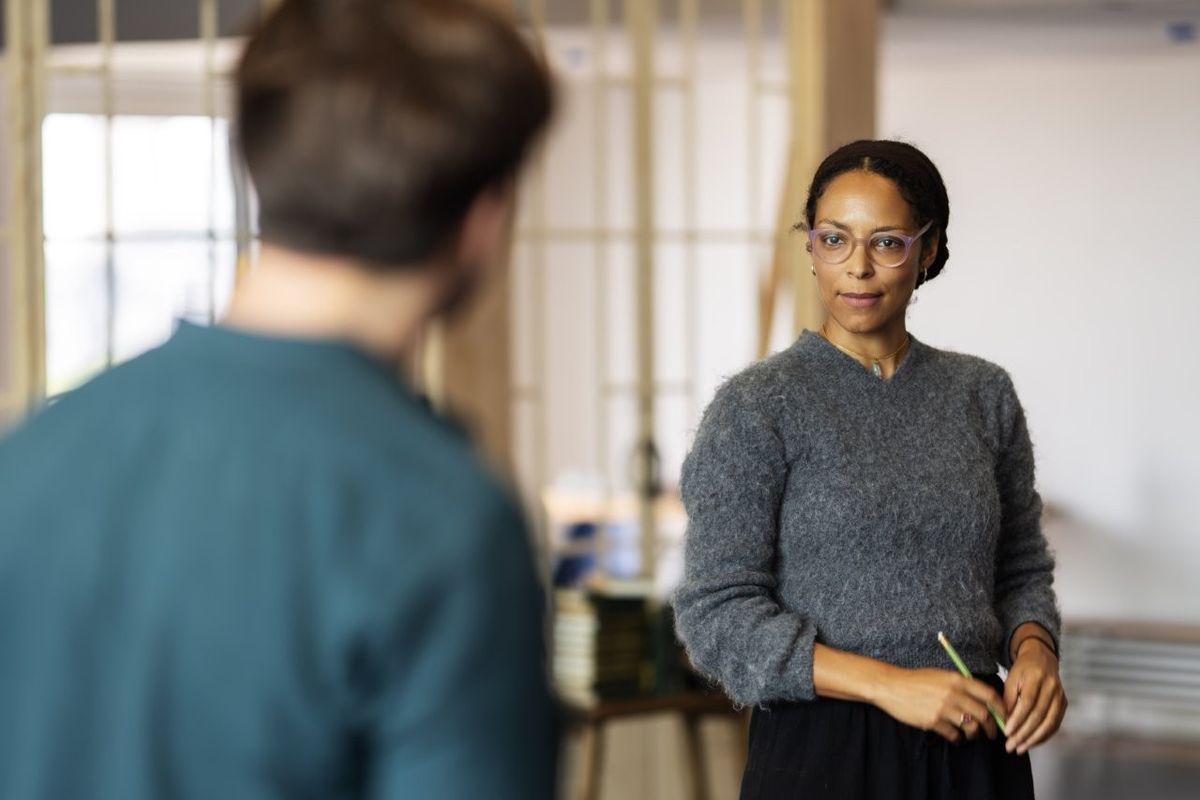 A man and a woman are stood facing each other, the woman is staring straight at the man