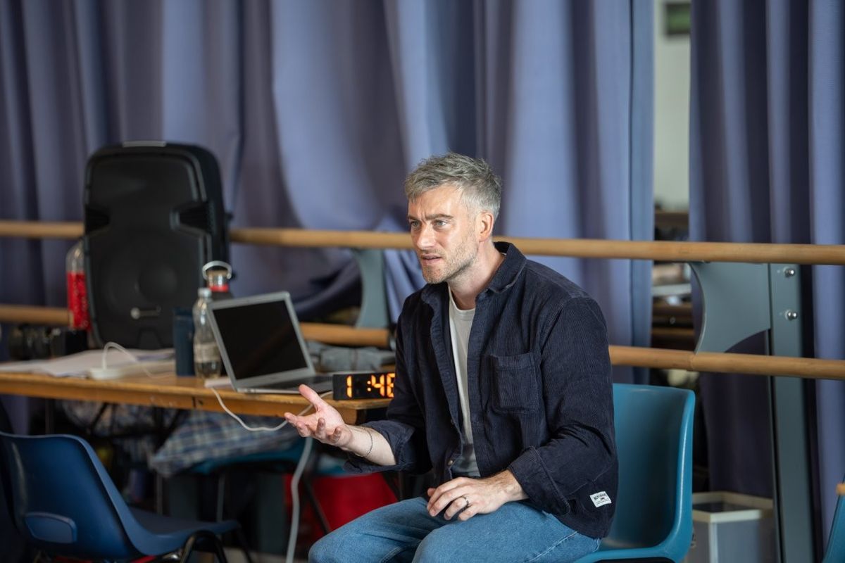 A man sat on a chair looking on in a neutral state