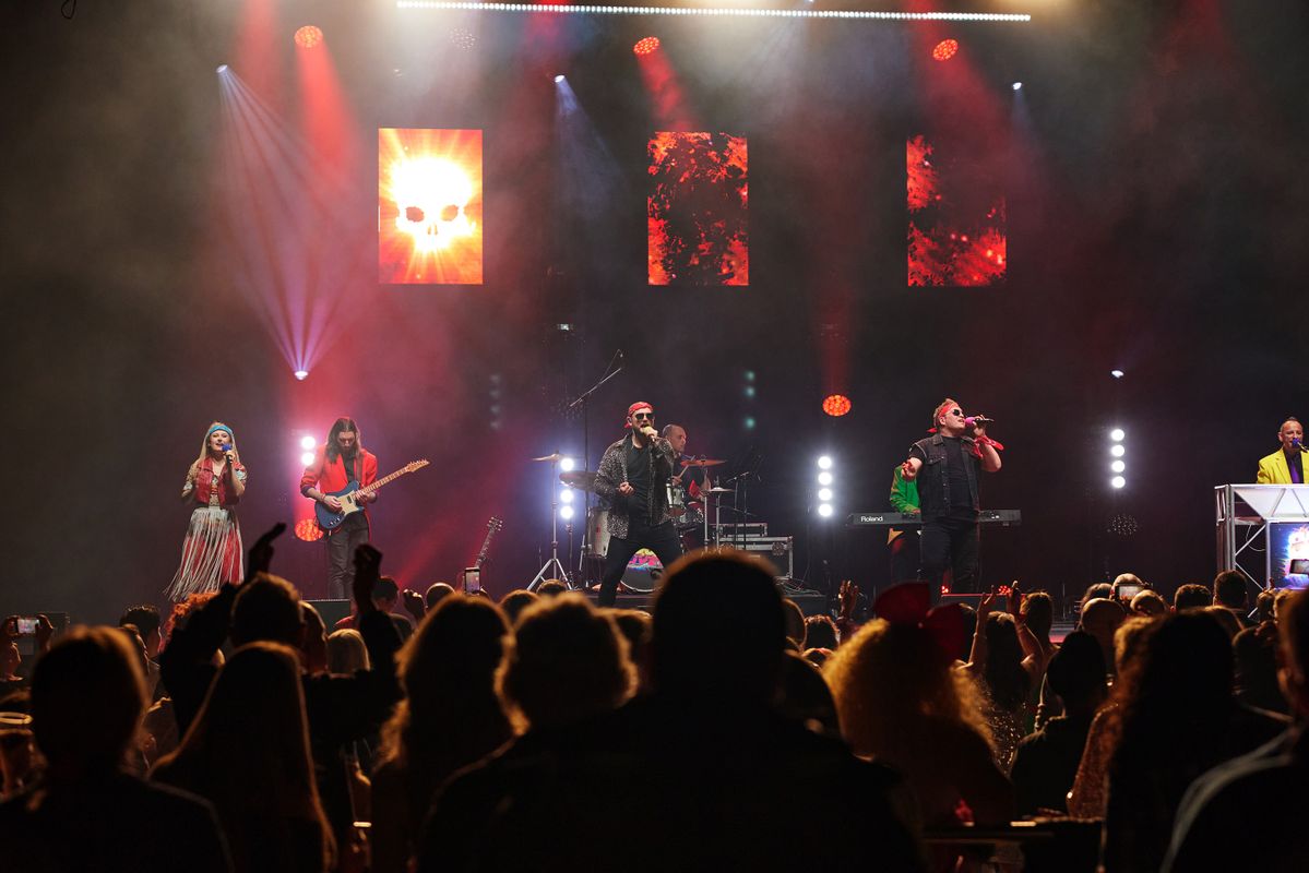 An audience watches three singers on stage.