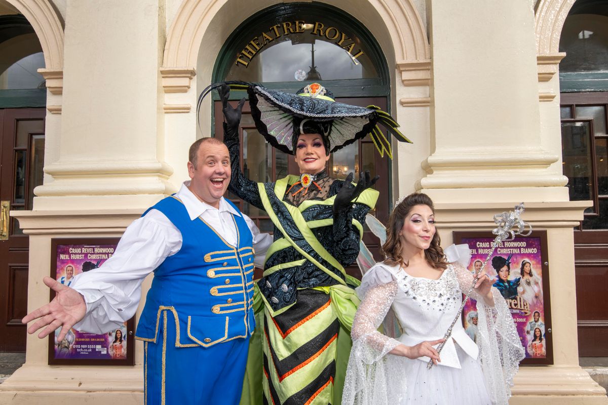 Buttons, the wicked stepmother and fairy stand outside the Theatre Royal entrance with gleeful expressions.