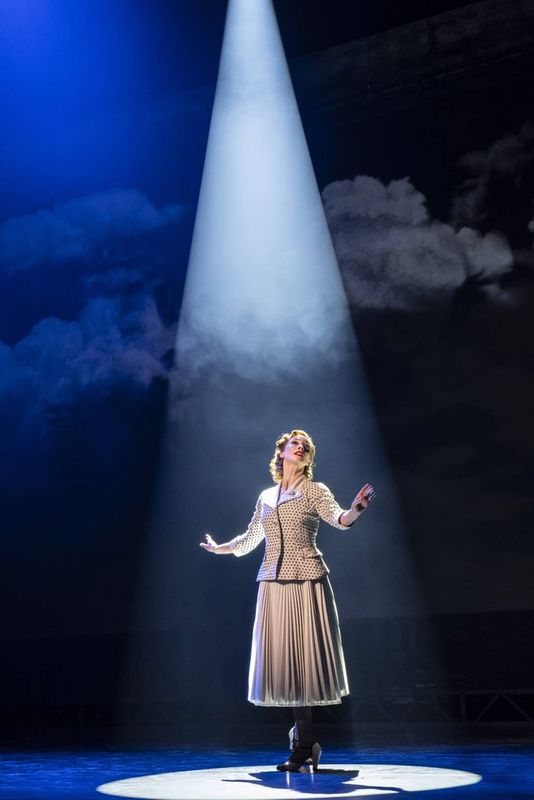 A person stands on stage in a spotlight.