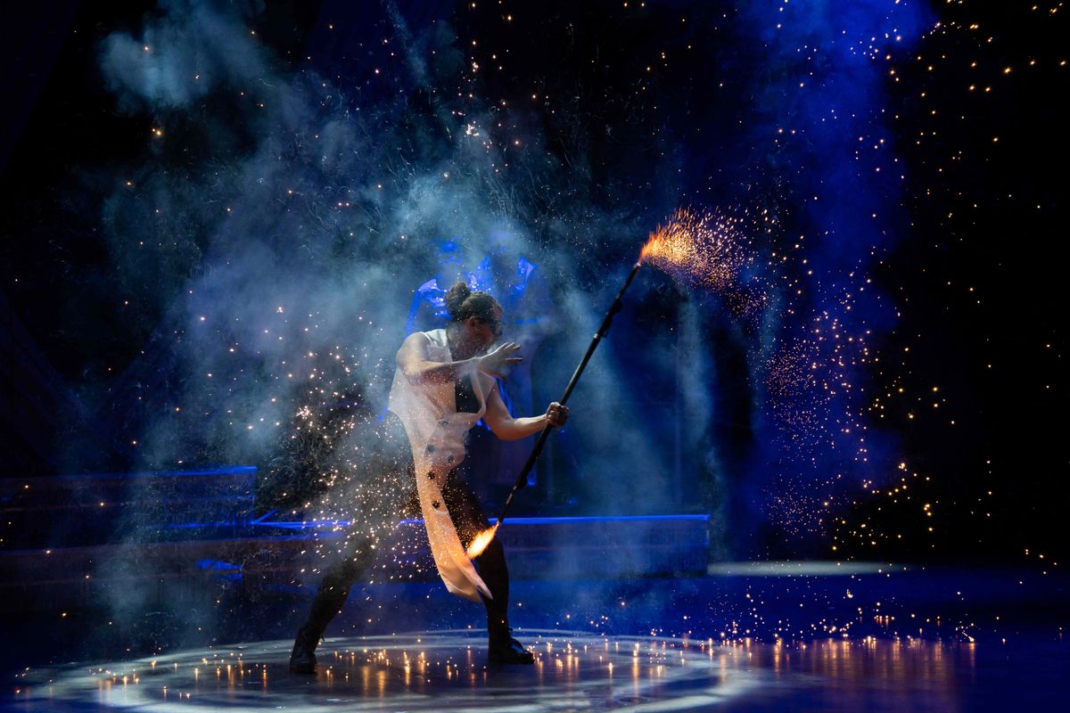 A circus performer holds a baton with fire on both ends.