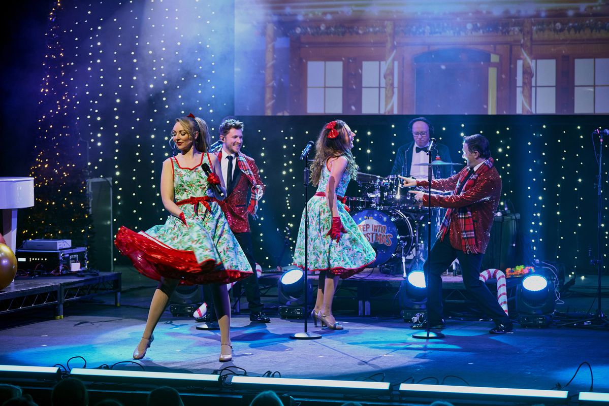 Performers on stage singing and dancing in a Christmas scene