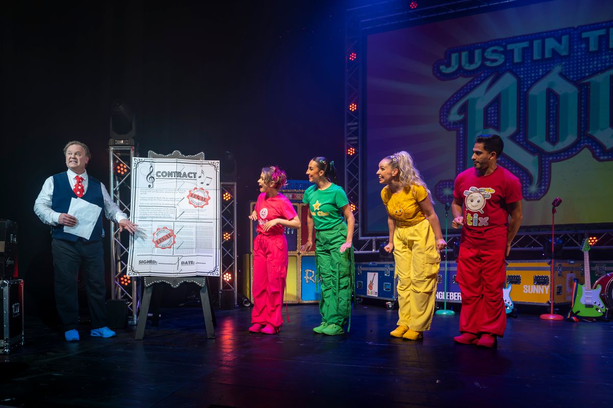 The whole company stand on stage wearing colourful outfits.