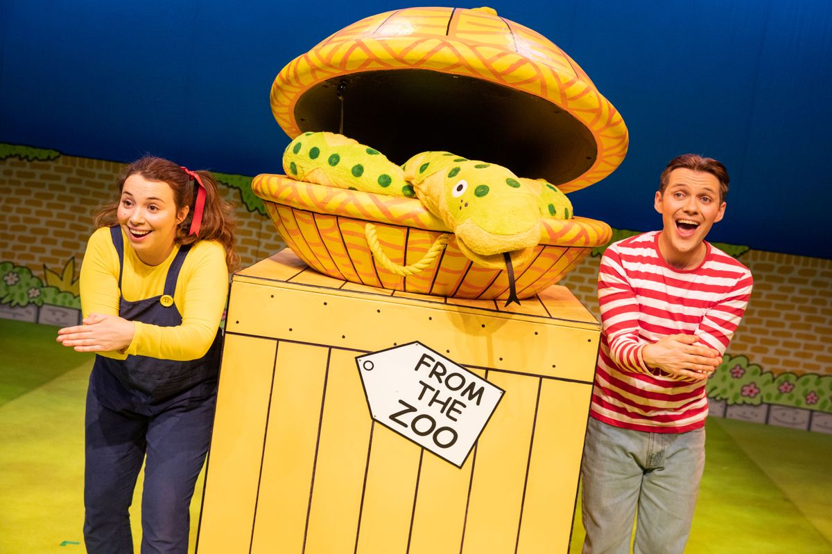 Two people stood either side a box with a basket on the top that has a puppet snake inside.