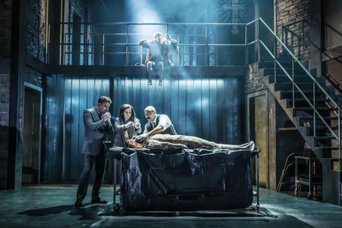 There are three people looking at a body on a examining table