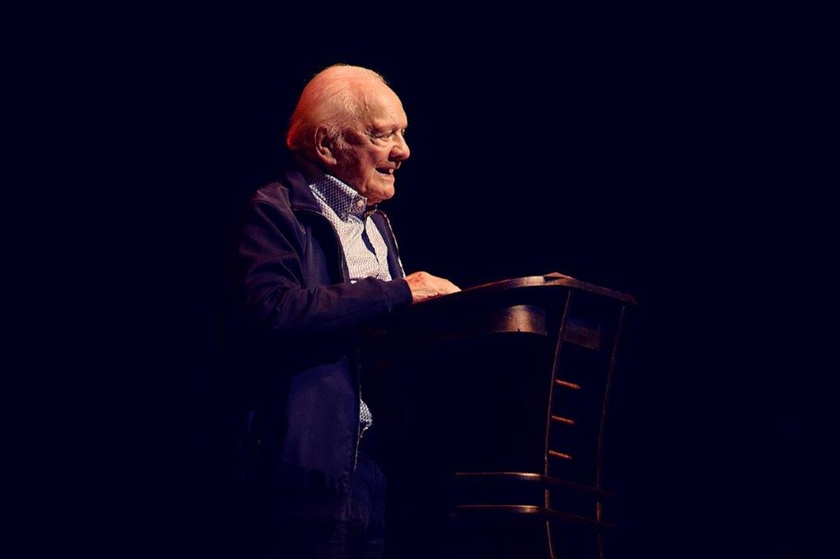 Sir David Jason is stood at a podium
