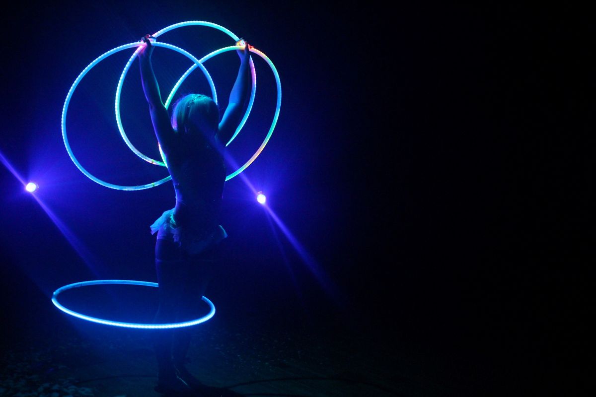 A circus performer uses glow in the dark hula hoops. 