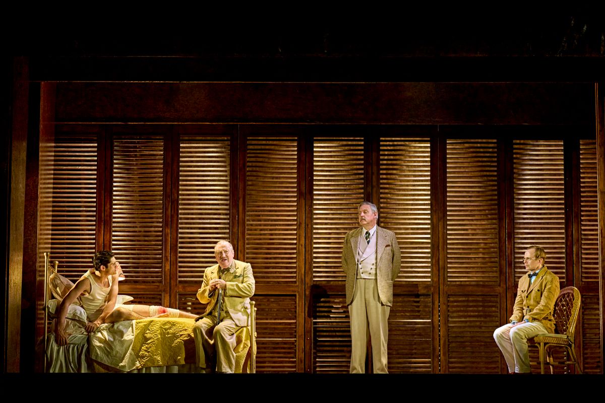 Four people have a discussion in a bedroom.