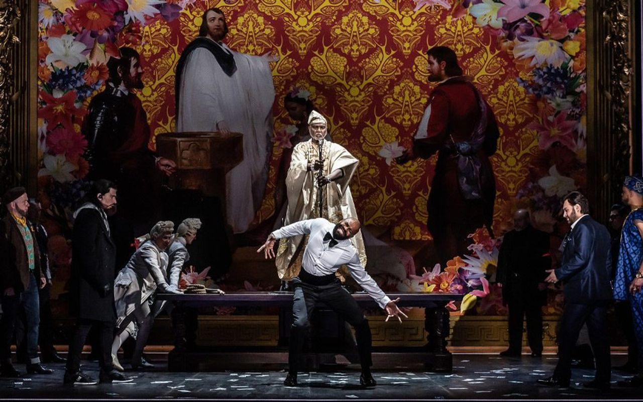 A group of people in a religious setting. Someone is stood on the table with a large staff. Person sat on the table looks to be in pain