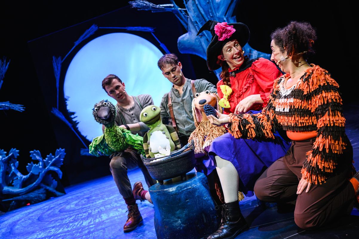 Group of actors onstage with animal puppets.