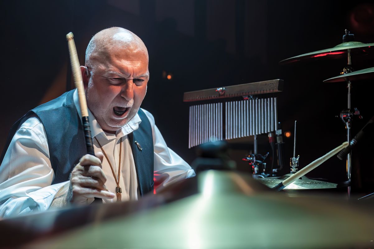 A person raises their drum stick to a cymbal.