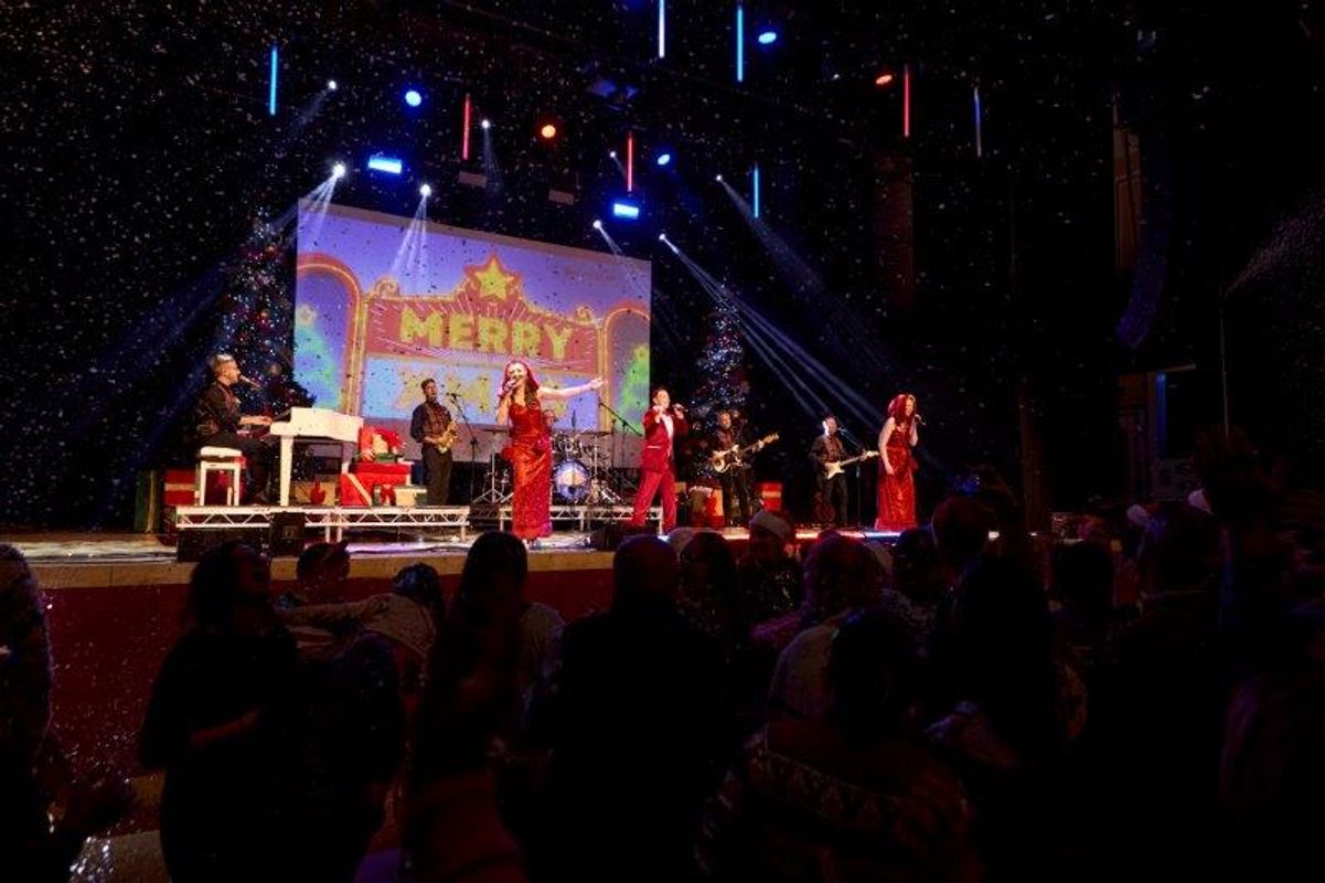 The audience watch four people singing on stage.
