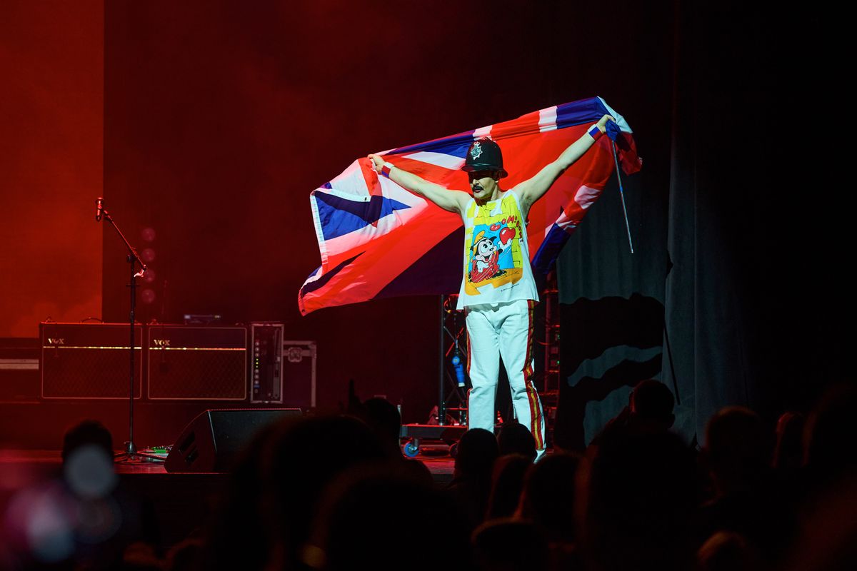 A man on stage holding a union jack flag and wearing a police hat