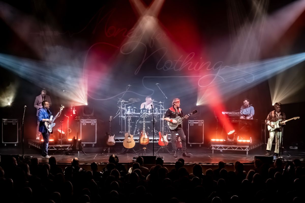 Band on stage performing, they're playing guitars and drums and there are flashing lights around them