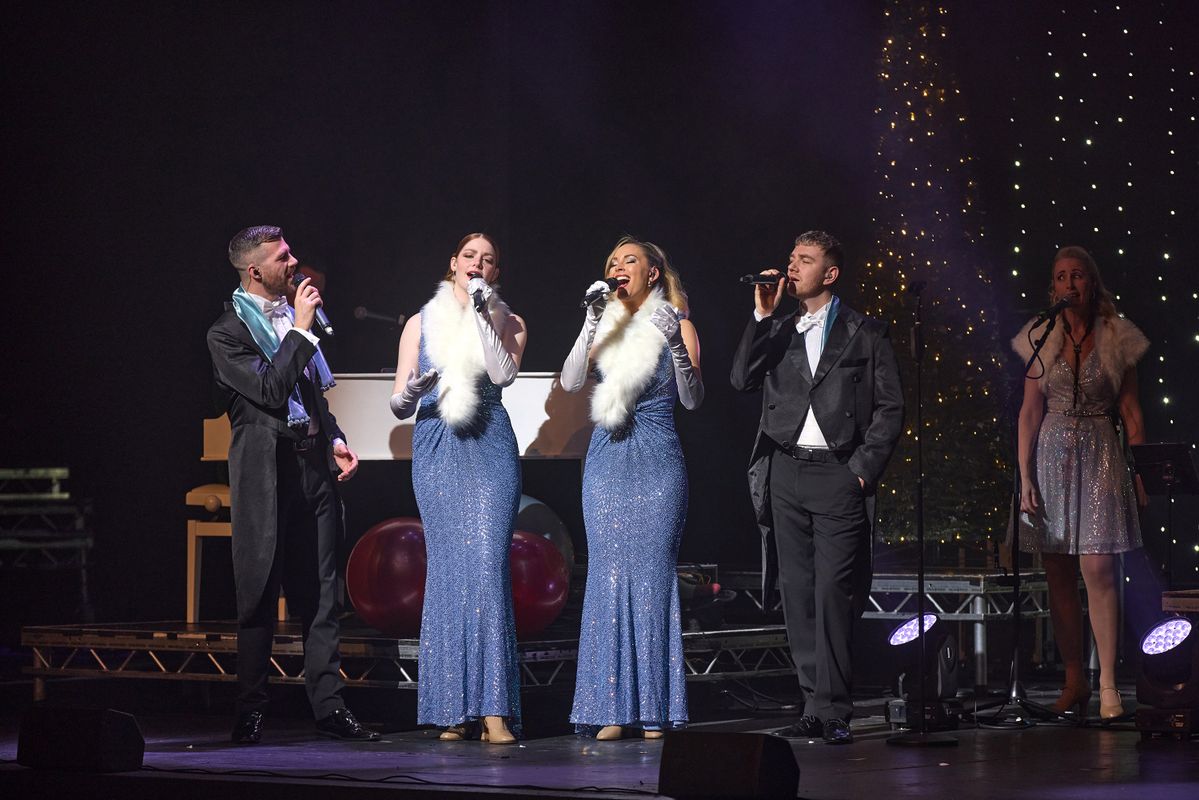 Performers on stage singing and dancing in a Christmas scene