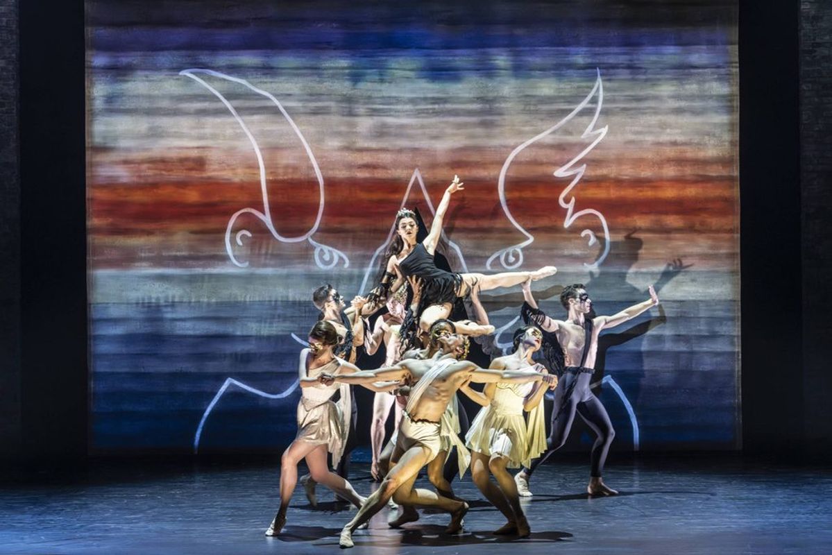 An ensemble of dancers hold a person in the air.
