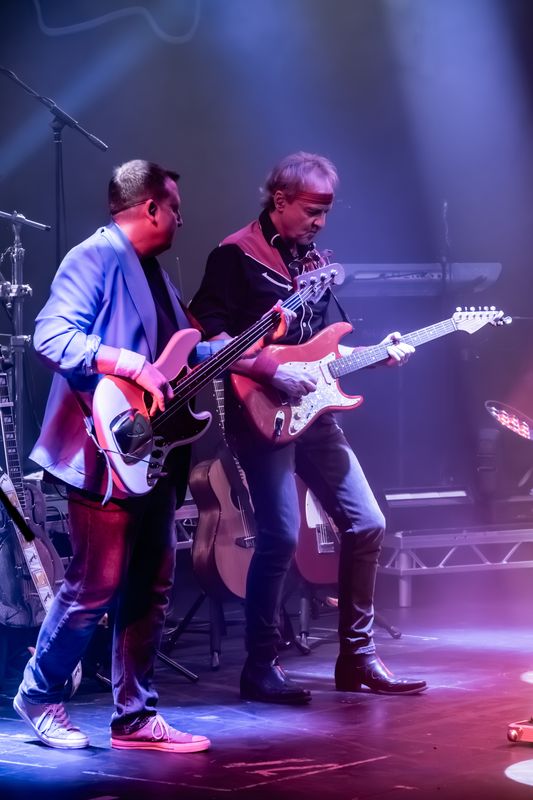 Two people play electric guitars on stage.