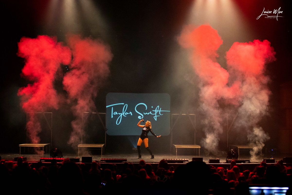 A singer stands centre stage surrounded by four smoke machines.