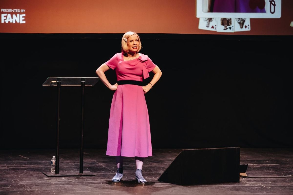 Lucy Worsley talking on stage. She is wearing a pink dress.