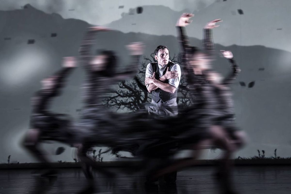 A person stands centre stage with their arms crossed in a shivering motion.