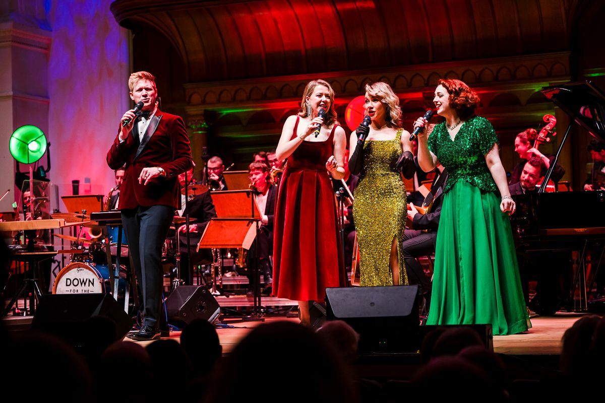 Four people stand on stage singing.