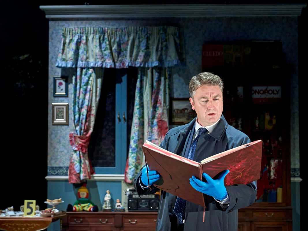 A person wearing a black coat and blue surgical gloves reads a book.