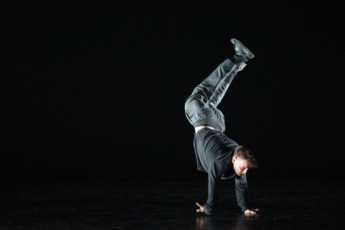 A person is captured mid move balancing on both arms with their lower legs bent in a curved motion.