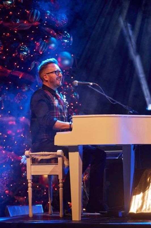 A person plays a white piano on stage.