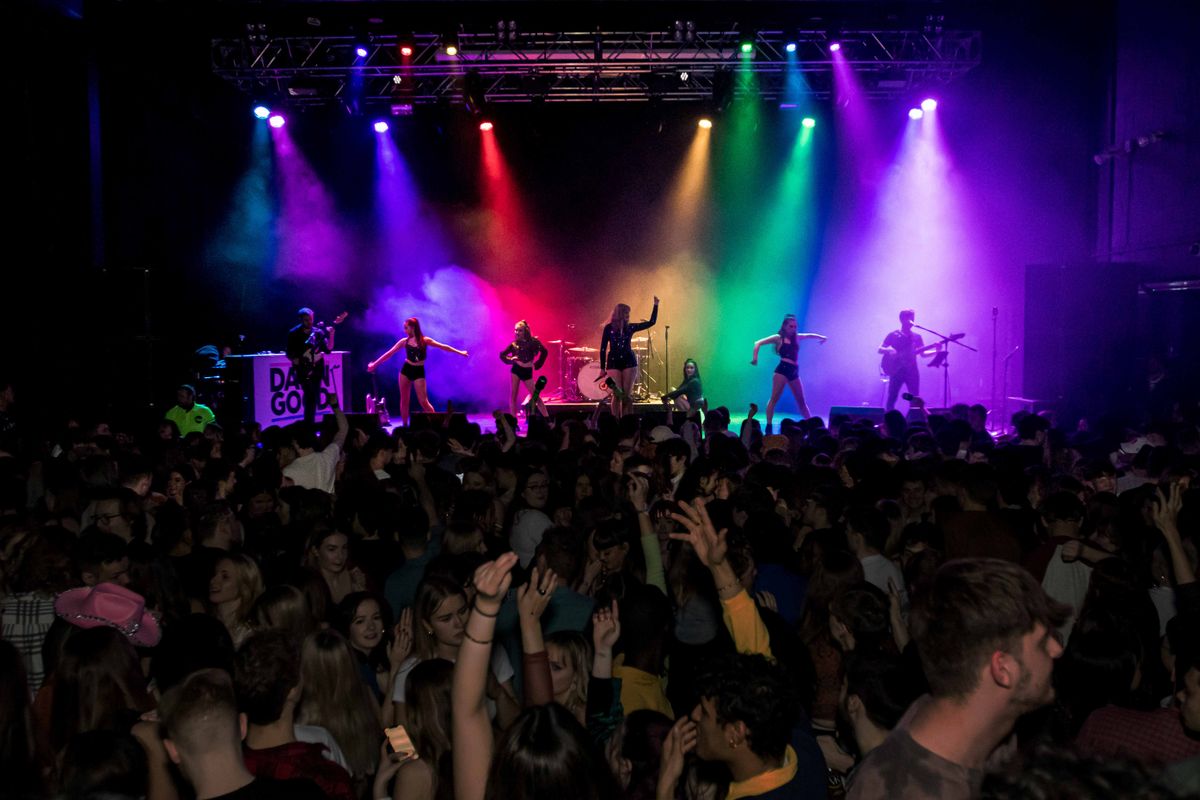 Rainbow colour spotlights highlight the performers on stage.